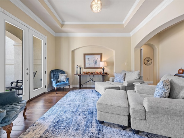 living room with a raised ceiling, french doors, dark wood-type flooring, and ornamental molding