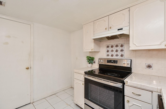 kitchen with tile countertops, stainless steel range with electric cooktop, decorative backsplash, light tile patterned flooring, and white cabinetry