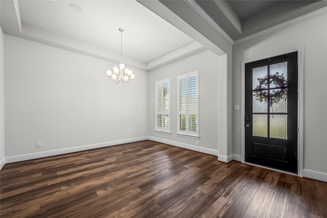 foyer entrance with a raised ceiling, dark hardwood / wood-style flooring, ornamental molding, and a chandelier