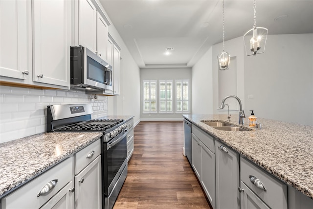 kitchen with appliances with stainless steel finishes, dark hardwood / wood-style floors, light stone counters, and sink