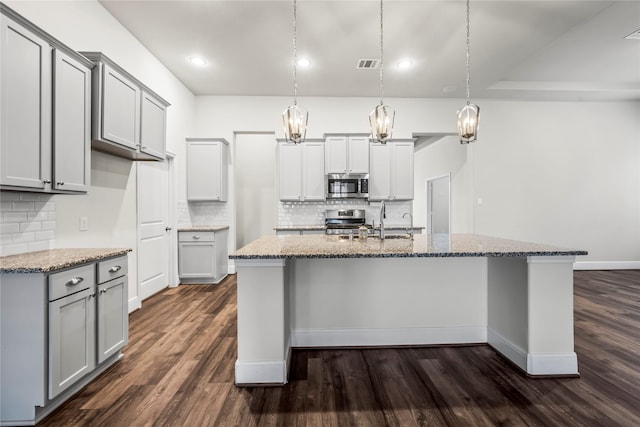 kitchen with an island with sink, stainless steel appliances, and dark hardwood / wood-style floors