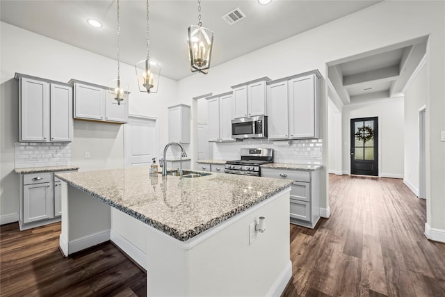 kitchen featuring sink, dark hardwood / wood-style flooring, pendant lighting, a center island with sink, and appliances with stainless steel finishes