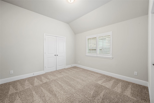 carpeted spare room with vaulted ceiling