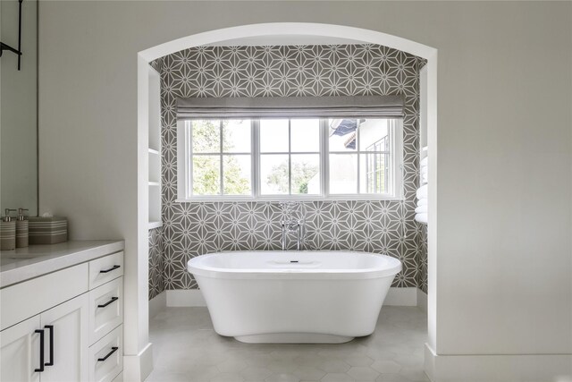 bathroom with tile patterned flooring, a healthy amount of sunlight, tile walls, and a tub