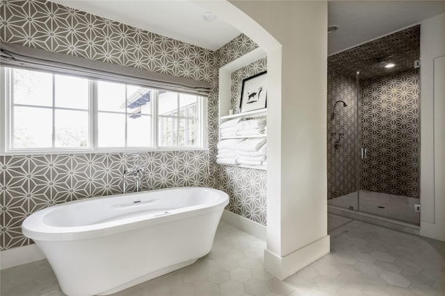 bathroom with plus walk in shower, tile patterned floors, and tile walls