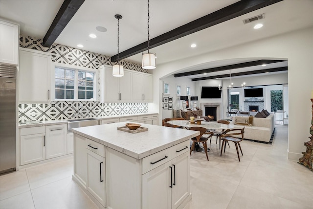 kitchen featuring white cabinets, beam ceiling, pendant lighting, and tasteful backsplash