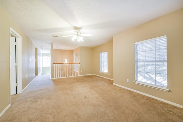 unfurnished room featuring ceiling fan, light colored carpet, and a textured ceiling