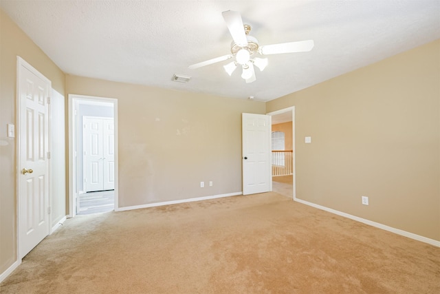 spare room with light carpet, ceiling fan, and a textured ceiling