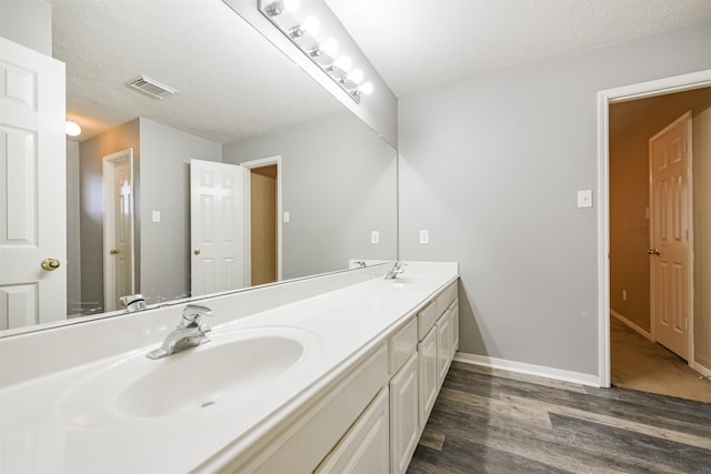 bathroom with a textured ceiling, vanity, and hardwood / wood-style flooring