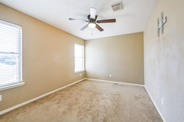 carpeted spare room featuring ceiling fan and a healthy amount of sunlight