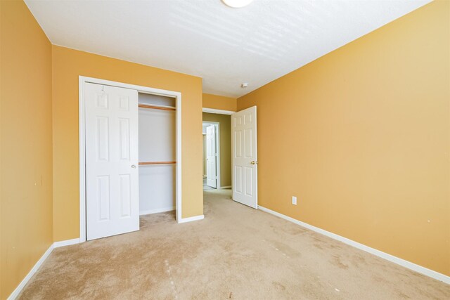 unfurnished bedroom with light carpet and a closet