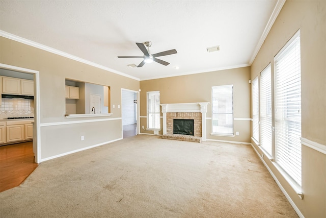 unfurnished living room with crown molding, a fireplace, ceiling fan, and light carpet