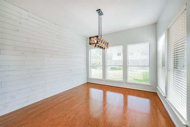 unfurnished dining area featuring hardwood / wood-style floors and wooden walls