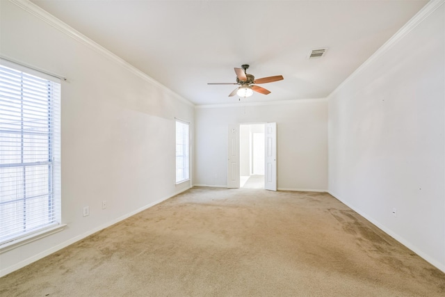 carpeted empty room featuring ceiling fan, ornamental molding, and a wealth of natural light