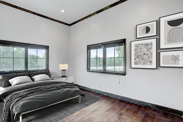 bedroom featuring hardwood / wood-style flooring, ornamental molding, and multiple windows