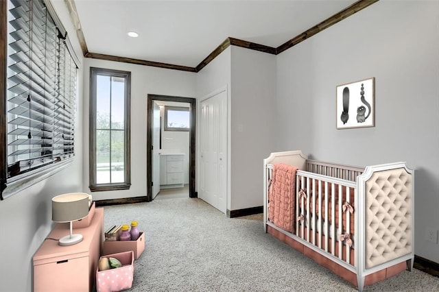 carpeted bedroom featuring a nursery area and ornamental molding