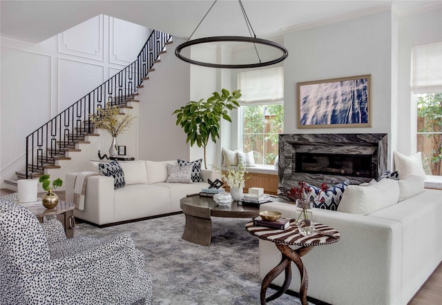 living room featuring a high end fireplace, plenty of natural light, and ornamental molding