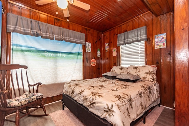 bedroom featuring ceiling fan, wooden walls, wood-type flooring, and wooden ceiling