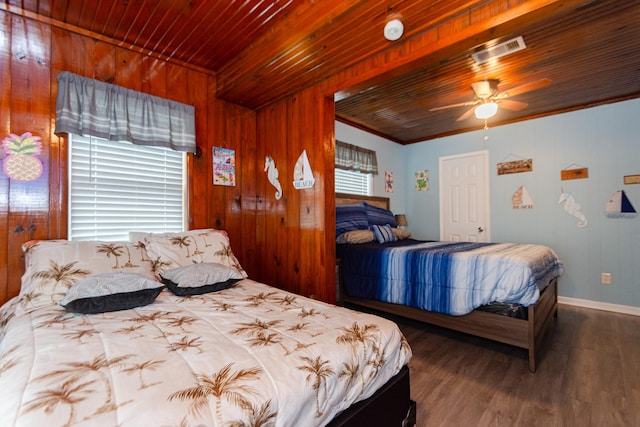 bedroom with ceiling fan, wooden ceiling, dark wood-type flooring, crown molding, and wooden walls