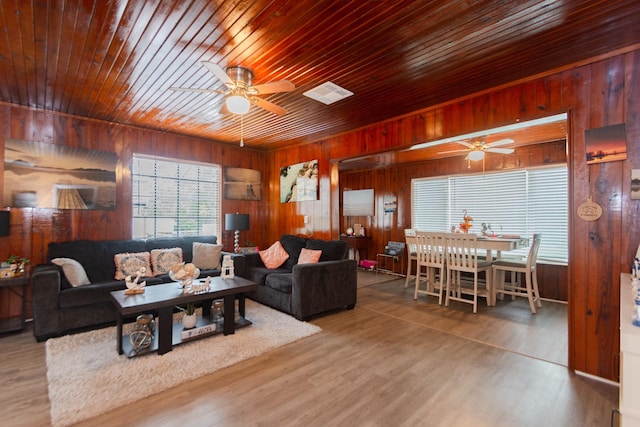 living room featuring ceiling fan and wood walls