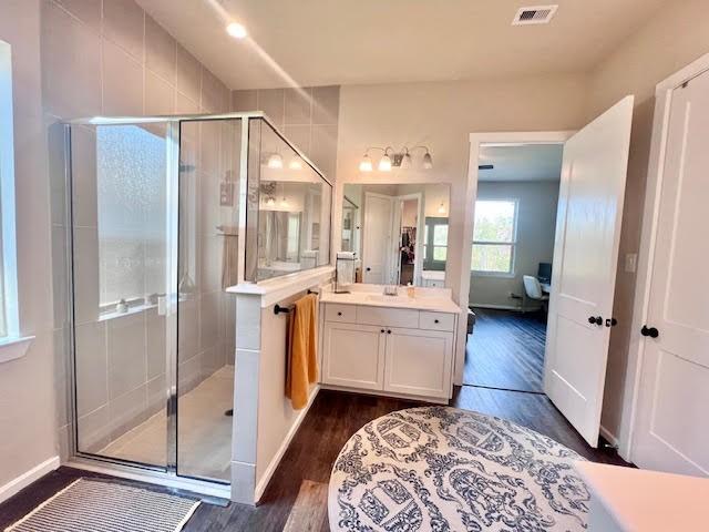 bathroom with hardwood / wood-style floors, vanity, and an enclosed shower