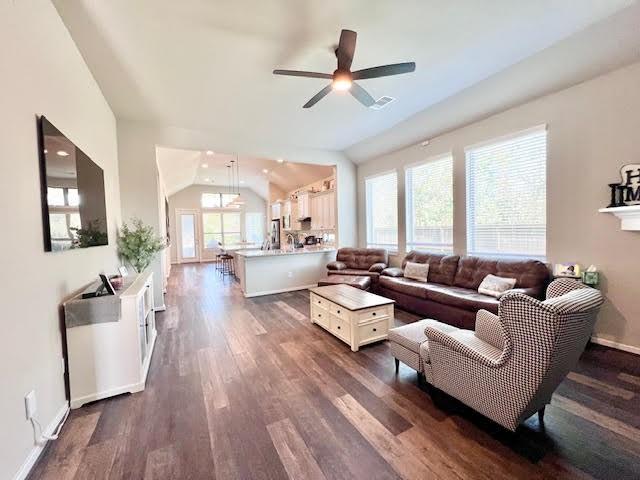 living room with ceiling fan, dark hardwood / wood-style flooring, a healthy amount of sunlight, and vaulted ceiling