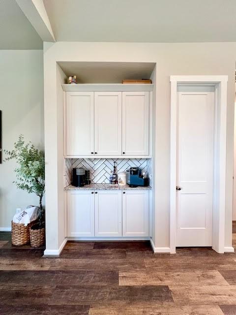 bar featuring decorative backsplash, hardwood / wood-style floors, and white cabinets