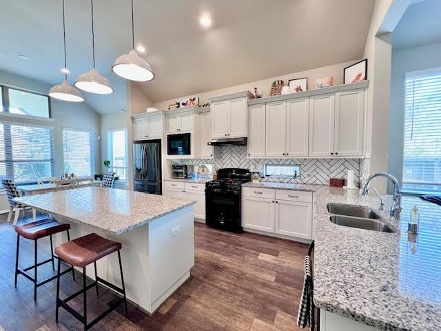 kitchen with dark hardwood / wood-style flooring, vaulted ceiling, sink, black appliances, and decorative light fixtures