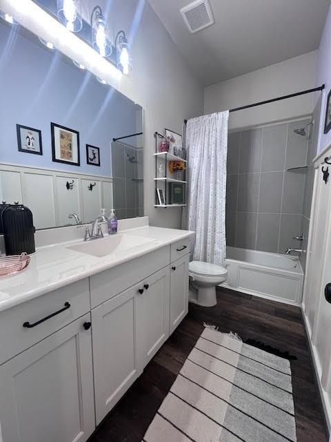 full bathroom featuring shower / bath combo, wood-type flooring, vaulted ceiling, toilet, and vanity