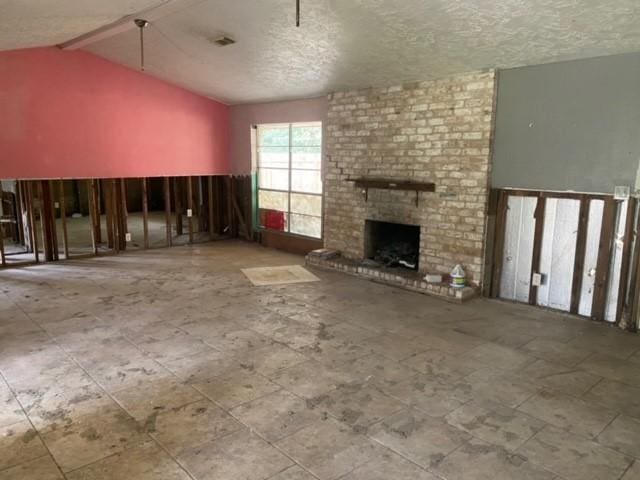 unfurnished living room with vaulted ceiling with beams, a fireplace, and a textured ceiling