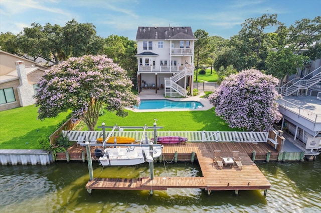 rear view of house with a pool side deck with water view, a balcony, and a yard