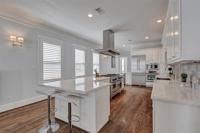 kitchen featuring sink, light stone counters, built in appliances, island range hood, and white cabinets