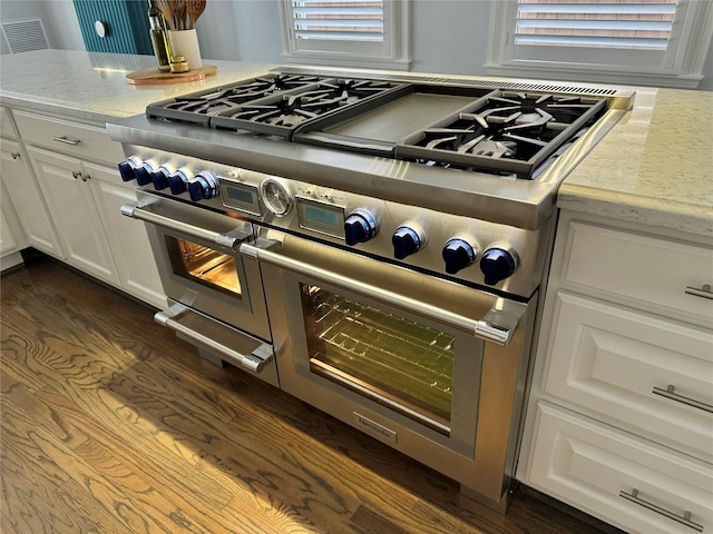 room details featuring white cabinets, dark hardwood / wood-style flooring, double oven range, and light stone counters