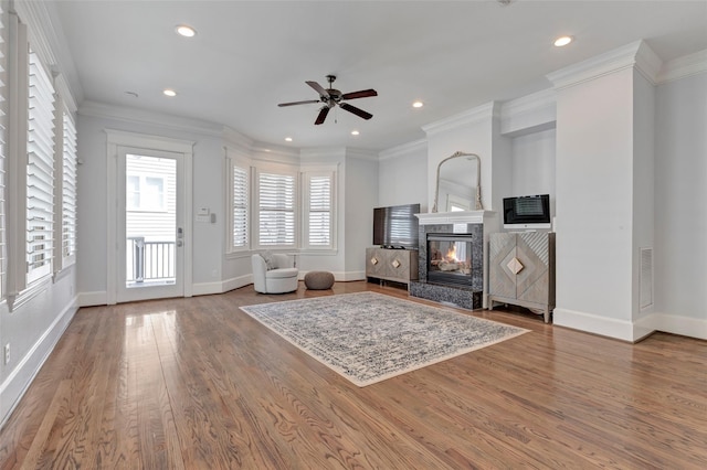 living room with a multi sided fireplace, hardwood / wood-style flooring, ceiling fan, and ornamental molding