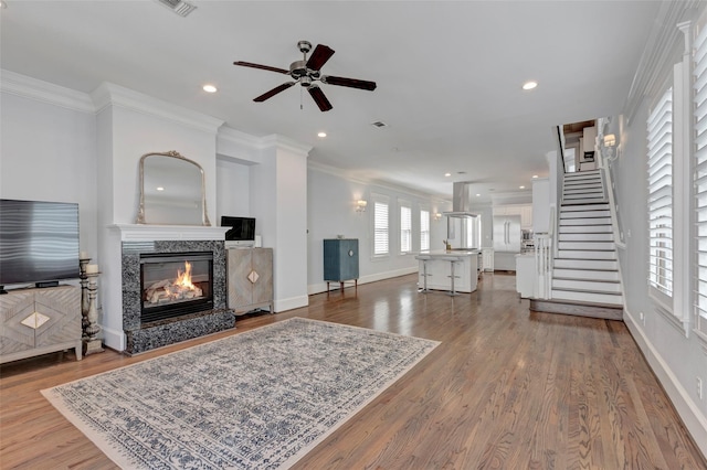 living room featuring plenty of natural light, a high end fireplace, hardwood / wood-style floors, and ornamental molding