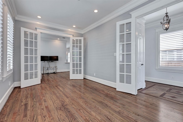 empty room with a chandelier, french doors, dark wood-type flooring, and ornamental molding