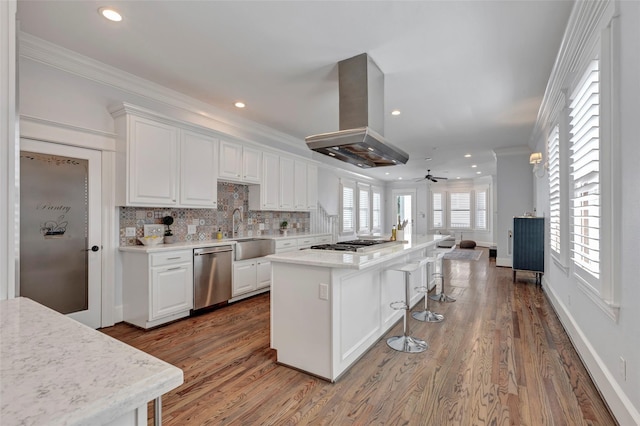 kitchen with island exhaust hood, appliances with stainless steel finishes, a center island, and white cabinets