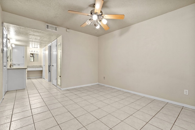 tiled empty room featuring a textured ceiling and ceiling fan