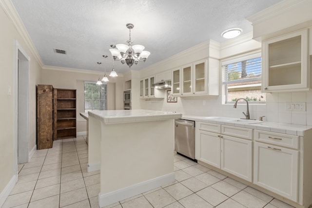 kitchen featuring white cabinetry, sink, a center island, tile counters, and appliances with stainless steel finishes