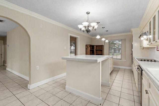 kitchen featuring tile countertops, ornamental molding, light tile patterned floors, a kitchen island, and a chandelier