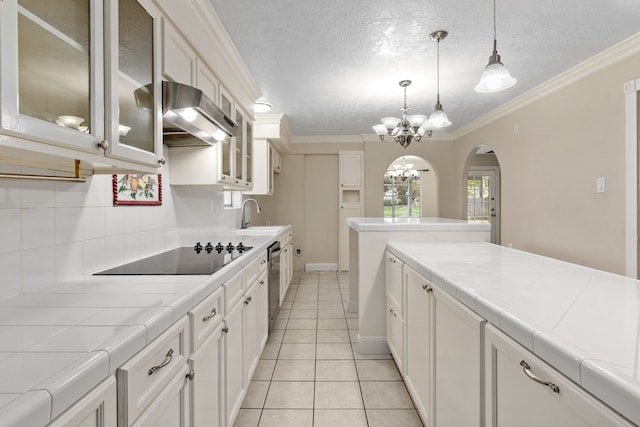 kitchen featuring tile countertops, white cabinets, and range hood