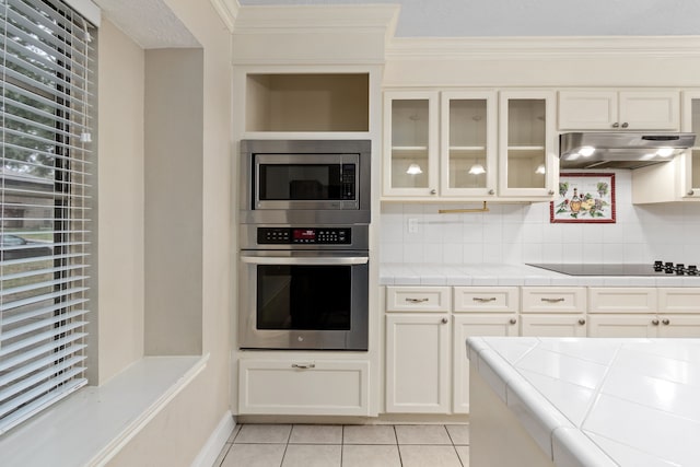 kitchen featuring light tile patterned floors, backsplash, appliances with stainless steel finishes, and ornamental molding