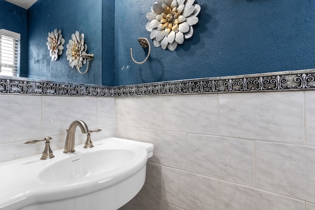 bathroom featuring sink and tile walls