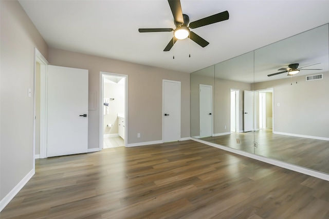 spare room featuring dark wood-type flooring, a ceiling fan, visible vents, and baseboards