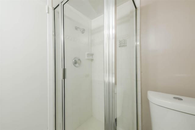 full bathroom featuring a shower stall and toilet