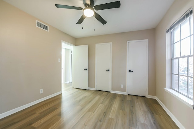 unfurnished bedroom with light wood-style floors, visible vents, baseboards, and a ceiling fan