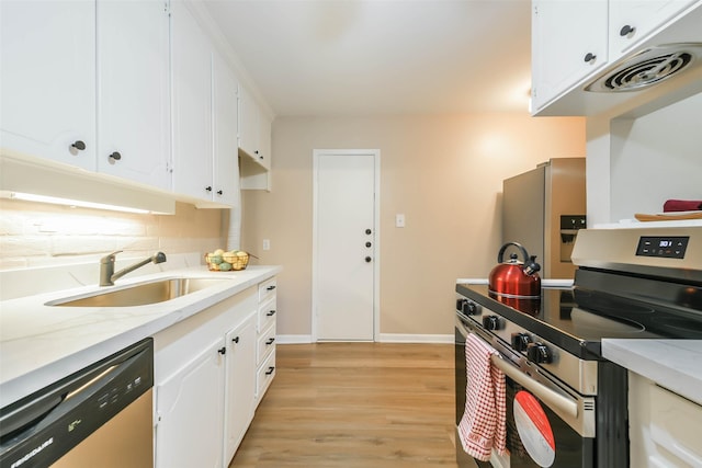 kitchen featuring appliances with stainless steel finishes, light wood-type flooring, a sink, and white cabinetry