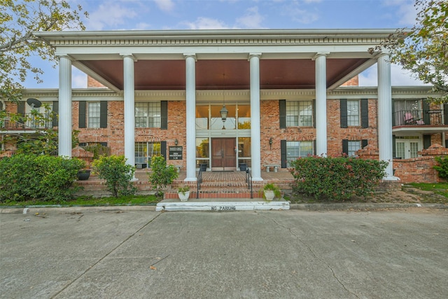 greek revival inspired property featuring brick siding and a porch