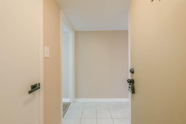 hall featuring light tile patterned flooring and baseboards