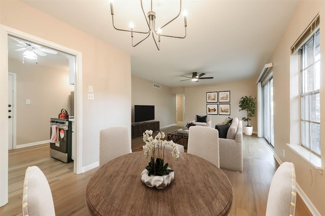 dining area with light wood-style floors, visible vents, baseboards, and ceiling fan with notable chandelier